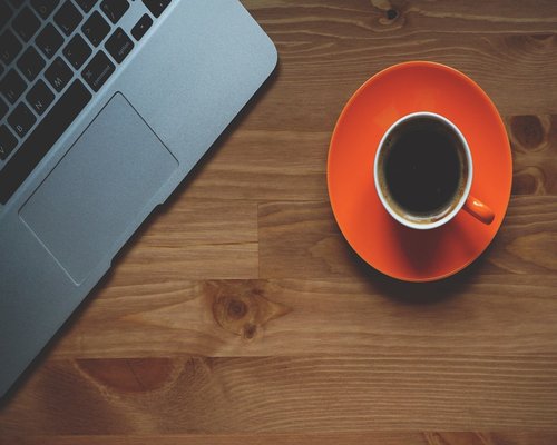 A cup of coffee and a notebook on a modern office desk